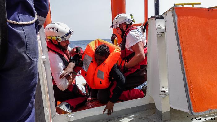 Two men help an exhausted rescued woman on board the Aquarius (DW/F. Warwick)