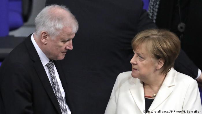 German Interior Minister Horst Seehofer, left, talks to German Chancellor Angela Merkel