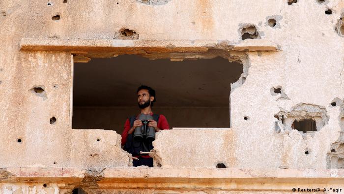A fighter holding binoculars looks out of a damaged building (Reuters/A. Al-Faqir)