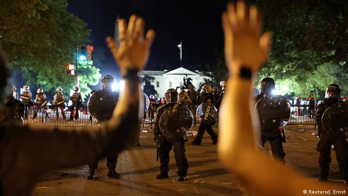 Protesters hold their hands up in front of law enforcement personnel as demonstrators rally at the White House
