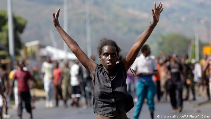 A demonstrator raises her hands in the air as she faces soldiers in the Musaga neighborhood of Bujumbura, Burundi ( AP Photo/Jerome Delay)
