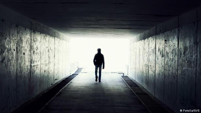 Homem caminha em direção a luz no fim de túnel