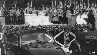 Hitler gives a speech before cars as Nazis look on (AP)