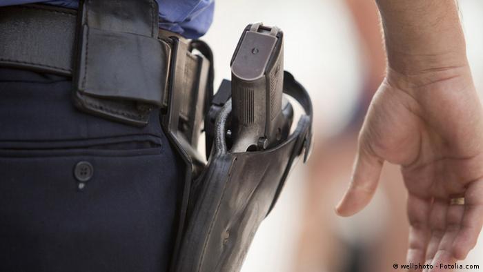 Рука полицейского крупным планом возле кобуры с пистолетом