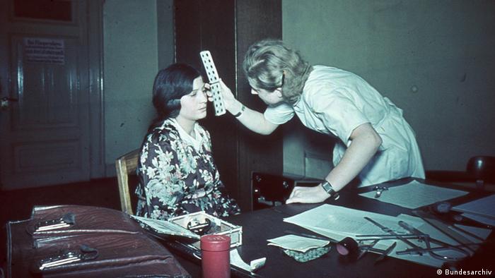 A woman measures another's face