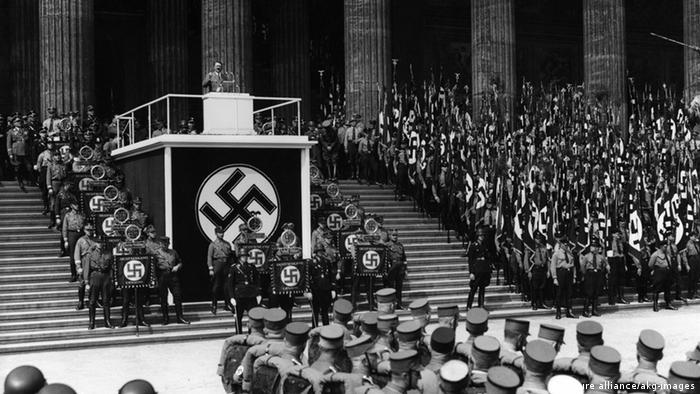 Berlin, 1936. Hitler speaks to crowds from a stage set on stairs, huge swastika (picture alliance/akg-images)