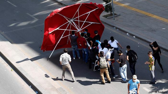The photo shows demonstrators in Istanbul using a large parasol to protect themselves from water cannons.