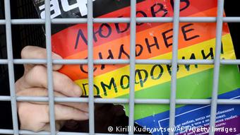 Рука за решеткой держит плакат любовь сильнее гомофобии