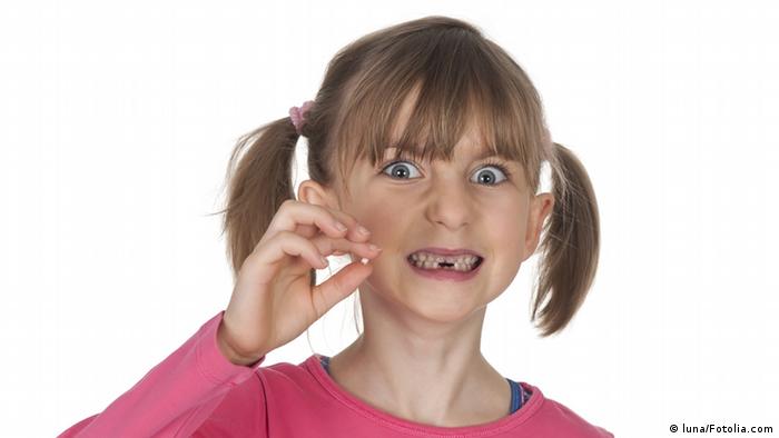Foto de menina com dente de leite decíduo