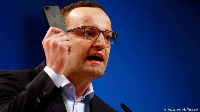 Jens Spahn holds a mobile phone in his hand as he speaks during the Christian Democratic Union (CDU) party convention