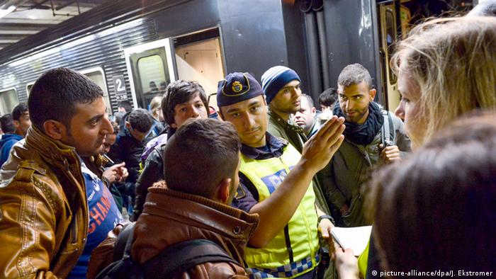 Migrants get directions from a policeman at a train station in Stockholm in 2015