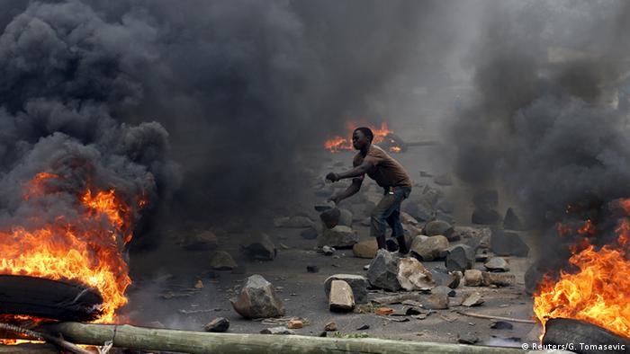 A protester in Bujumbura amid rubble and fires (Reuters/G. Tomasevic)