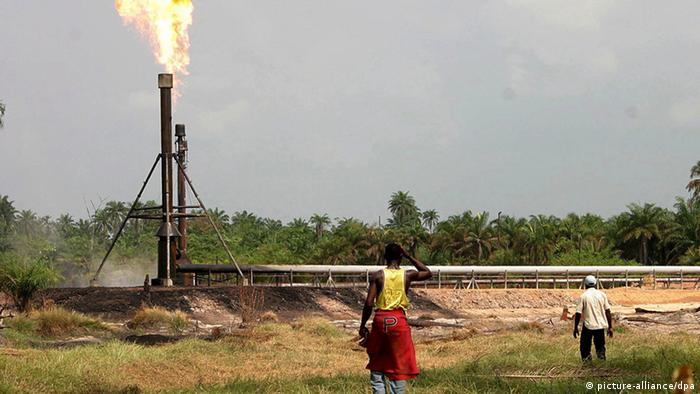 Two people looking at the flame spurting from an oil well (picture-alliance/dpa)