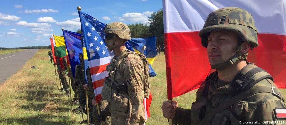 Soldados com bandeiras de todos os países da Otan enfileirados na fronteira leste da Aliança