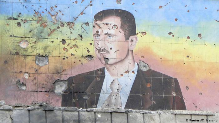 A picture of Assad painted on a wall and riddled with bullet holes