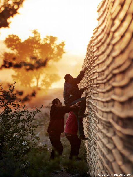 Símbolo del aislamiento. Migrantes latinoamericanos escalan la valla fronteriza. (Getty Images/S.Olson)