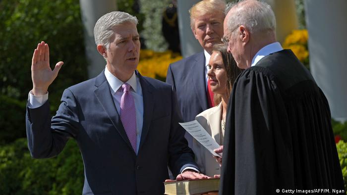 US President Donald Trump (C) watches as Justice Anthony Kennedy (R) administers the oath of office to Neil Gorsuch (L)as an associate justice of the US Supreme Court in the Rose Garden of the White House on April 10, 2017 in Washington, DC. 