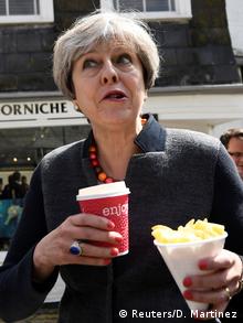 Britain's Prime Minister Theresa May enjoys some chips during a campaign stop in Mevagissey, Cornwall (Reuters/D. Martinez)