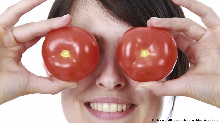 Woman holding tomatoes in front of her eyes (picture-alliance/united-archives/mcphoto)