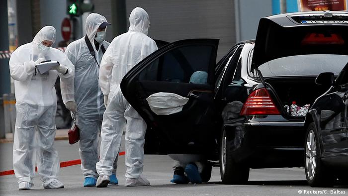 Forensic officers inspect the car in which a bomb in an envelope detonated in Athens