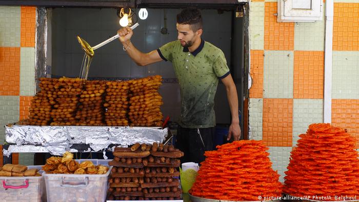 A man pors honey on cakes before breaking the fast during Ramadan (picture-alliance/AP Photo/A. Belghoul)