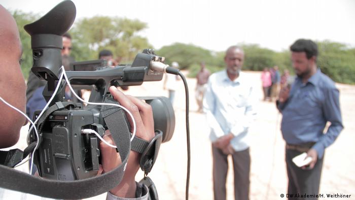 A journalist holds a camera, recording an interview