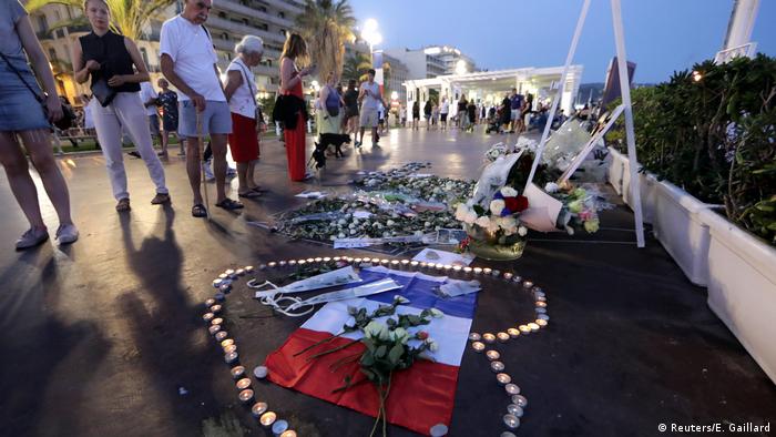 People look at candle tributes and flowers on the promenade boardwalk in Nice (Reuters/E. Gaillard)