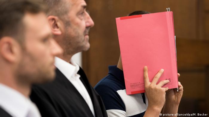 Foto de una persona en un juicio cubriéndose el rostro. 
