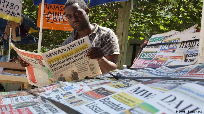 A man reads a newspaper at a newspaper stand in Tanzania