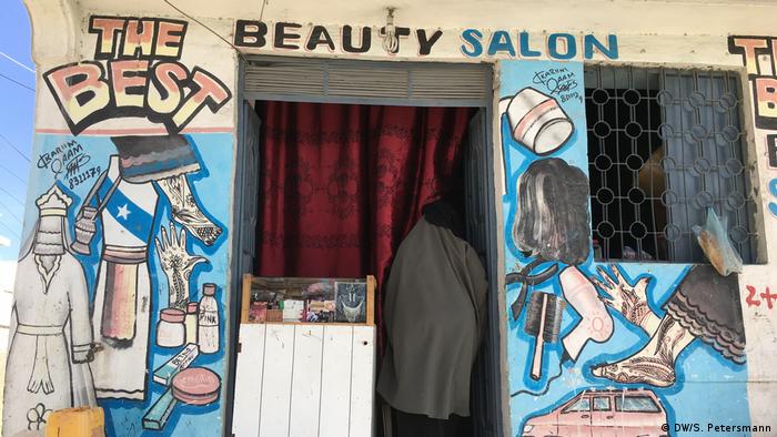 The painted front of a beauty salon shows pictures of beauty products, dresses, henna adorned hands and feet (DW/S. Petersmann)