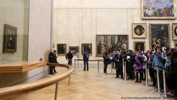 Visitantes contemplam e fotografam quadro da Mona Lisa no Louvre