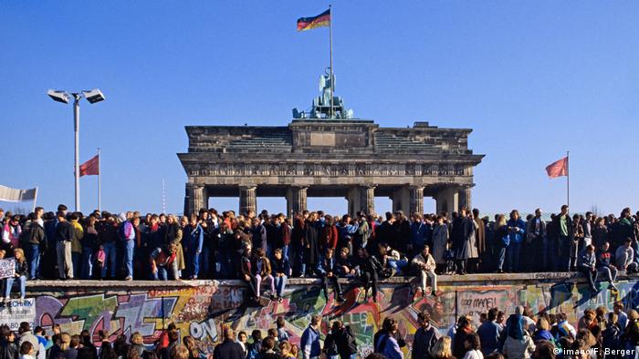 Centenas de pessoas passeiam em cima do Muro de Berlim, em frente ao Portão de Brandemburgo, em 1990