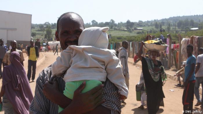 A man carries a baby on the run from ethnic violence in Ethiopia (DW/J. Jeffrey)