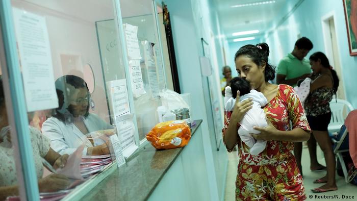 Mulher com bebê no colo em corredor de hospital