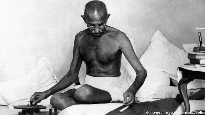 Gandhi sentado y escribiendo.