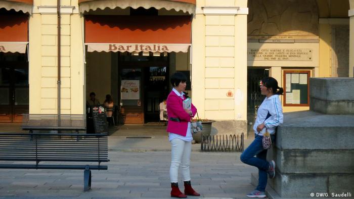Chinese women chat in the main square of Barge, Italy