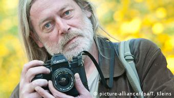 Fotógrafo Harald Hauswald segurando uma câmera fotográfica