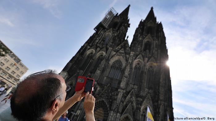 Tourist takes a photo of the Cologne Cathedral with his smartphone (picture-alliance/dpa/O. Berg)