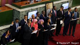 Cabinet members stand holding up their hands for the swearing in