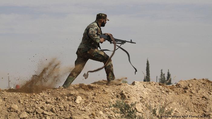 A sman running with a machine gun during fighting in Syria (picture-alliance/AP Photo/J.al-Helo)