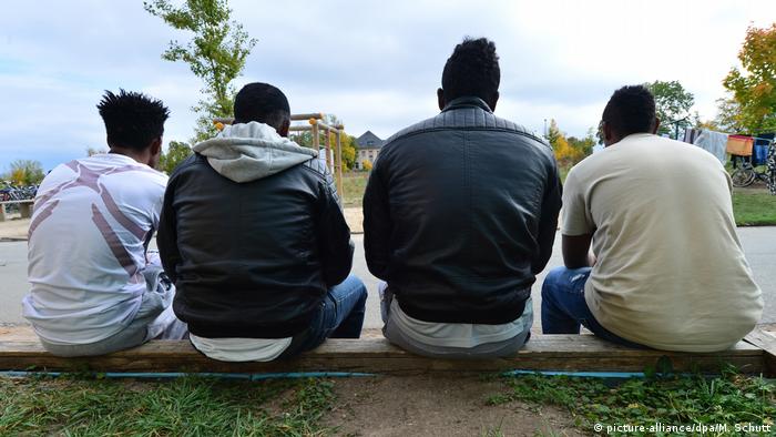 Four young men from Eritrea in Germany with their backs to the camera