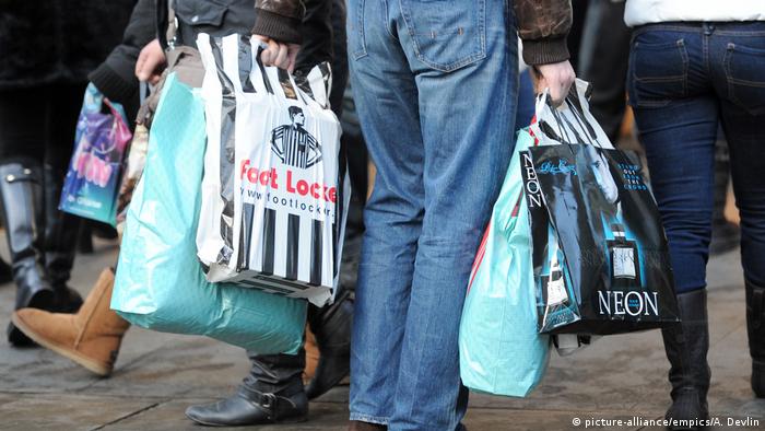 Personas con muchas bolsas de compra en una calle comercial.