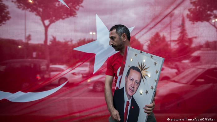 A man carries a picture of Turkish President Recep Tayyip Erdogan in front of a Turkish flag (picture-alliance/dpa/O.Weiken)