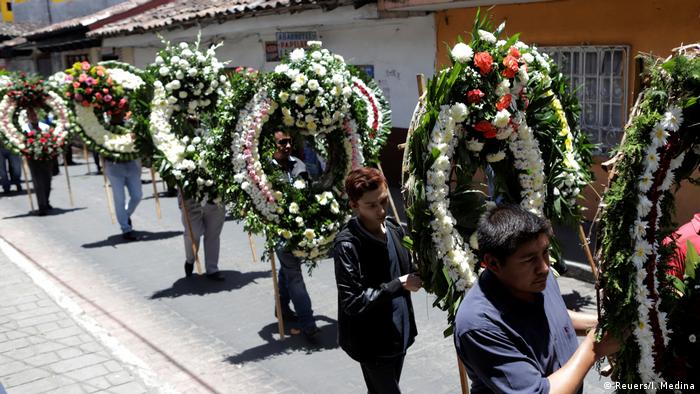 Mourners carry wreaths down a street (Reuers/I. Medina)
