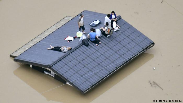 Only the rooftop of this house is above water, as where six people with a handful of belongings wait to be rescued.