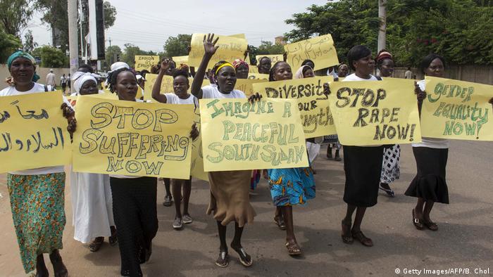 Women in South Sudan demonstrating for rights and peace hold up signs saying Stop rape now and Imagine a peaceful South Sudan