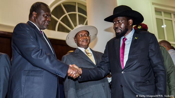 President Salva Kiir and opposition leader Riek Machar shake hands while Ugandan President Yoweri Museveni looks on.