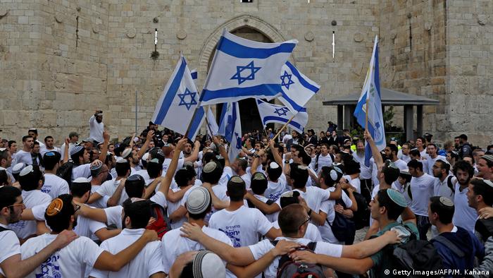 Nacionalistas israelenses, com baideiras de Israel, se abraÃ§am durante celebraÃ§Ã£o