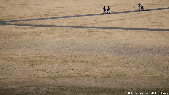 Visitors to Greenwich Park in London walk on the footpaths in between the dry brown grass