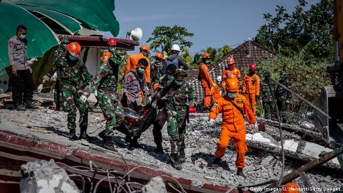 Indonesian soldiers and search and rescue teams carry the body of a victim